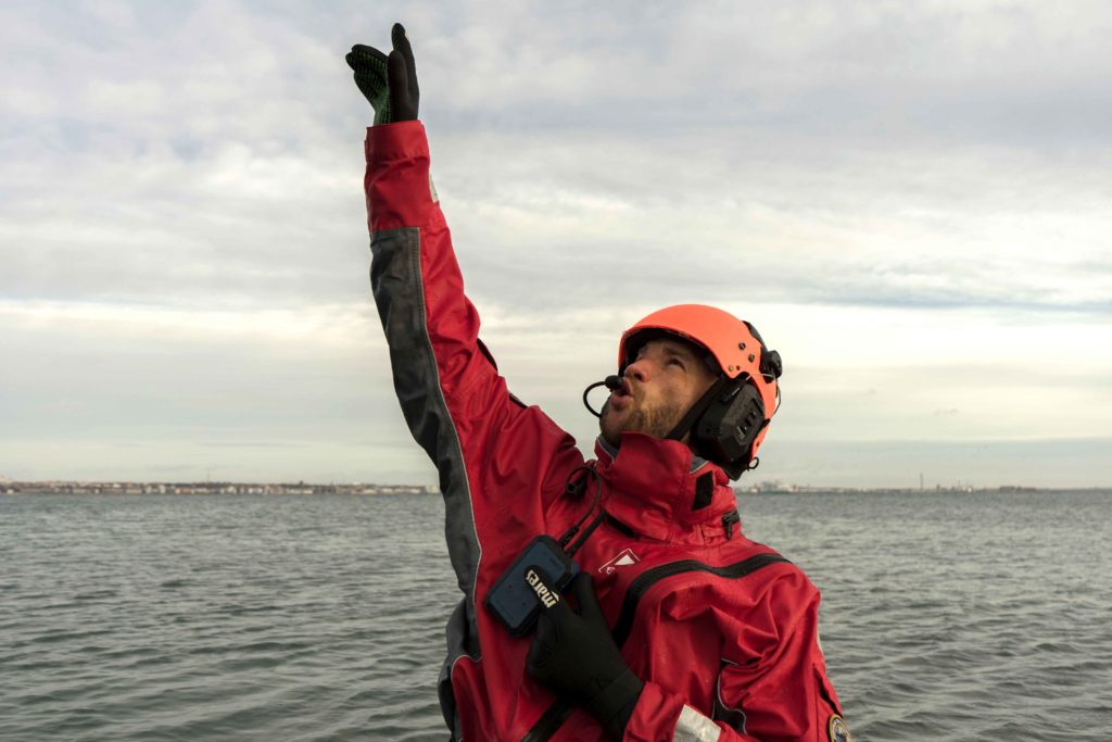 Man pointing to the sky in a drysuit and iwcs headset